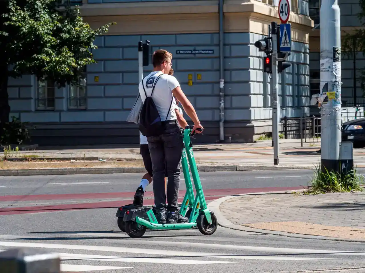 Persona circulando con un patinete no eléctrico por una acera junto a peatones