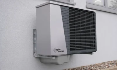Unidad exterior de aire acondicionado con bomba de calor instalada en la fachada de una casa moderna.
