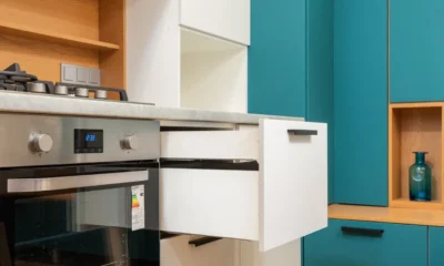 Cajon calientaplatos encastrable abierto bajo el horno con platos y tazas en una cocina moderna