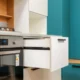 Cajon calientaplatos encastrable abierto bajo el horno con platos y tazas en una cocina moderna