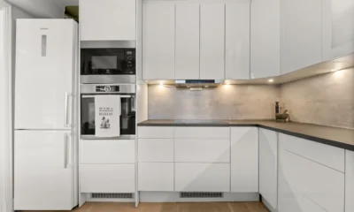 Cocina moderna con frigorificos panelables de colores integrados en los muebles y una puerta verde mate