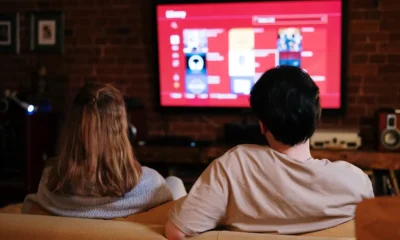 Pareja sentada en un salón moderno viendo un Televisor Smart TV 55 pulgadas: guía completa para elegir bien, con la pantalla de inicio de una app de streaming visible.