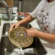 Persona cargando un lavavajillas abierto con platos limpios, imagen para el artículo Cuánta agua gasta un lavavajillas y qué factores cambian el consumo