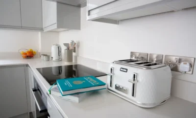 Dos robots de cocina sobre una isla moderna con etiquetas de precio y un libro de recetas abierto, ilustrando la Comparativa de robots de cocina: modelos, precios y claves
