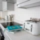 Dos robots de cocina sobre una isla moderna con etiquetas de precio y un libro de recetas abierto, ilustrando la Comparativa de robots de cocina: modelos, precios y claves