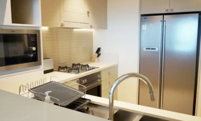 Persona descongelando un congelador en una cocina en verano, con escarcha, toallas y agua en el suelo mientras prepara la limpieza del aparato.