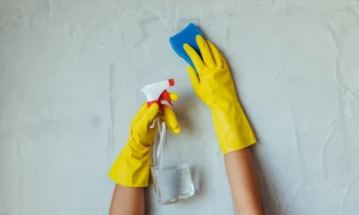 Persona limpiando la goma de una lavadora frontal con un paño y un spray de limpieza, imagen para el artículo Como quitar el mal olor de la lavadora sin dañarla