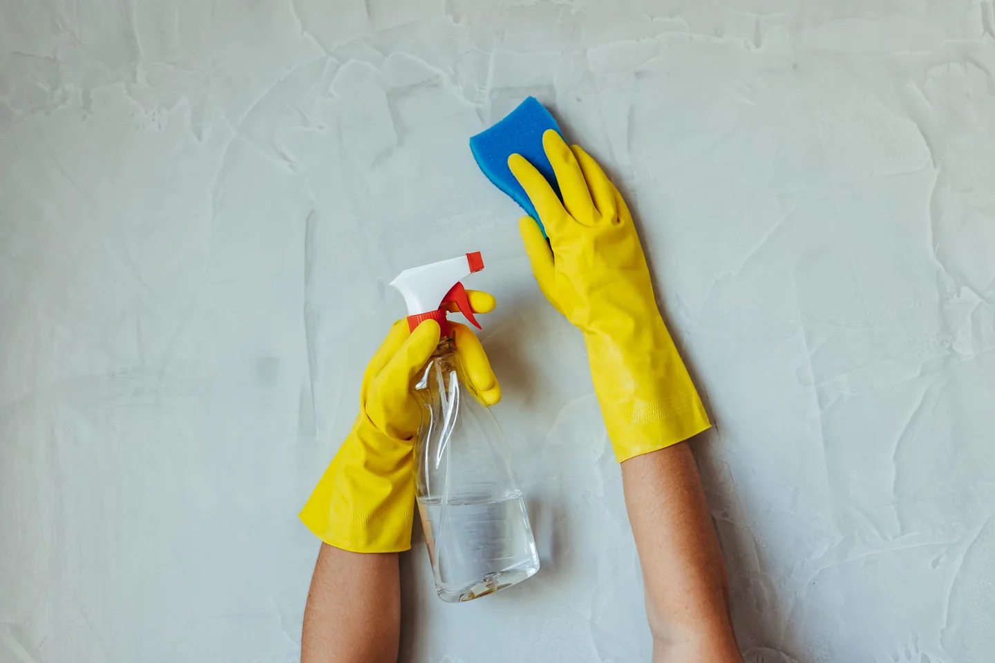 Persona limpiando la goma de una lavadora frontal con un paño y un spray de limpieza, imagen para el artículo Como quitar el mal olor de la lavadora sin dañarla