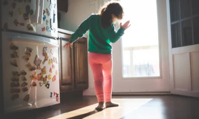 Persona inspeccionando la acumulación de hielo en la parte de atrás del frigorífico, imagen para el artículo "Mi frigorífico hace hielo en la parte de atrás: causas y arreglo".
