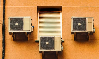 Técnico comprobando y recargando un aire acondicionado doméstico con manómetro y botella de refrigerante — Recargar el aire acondicionado de casa: cuándo es necesario y cuánto cuesta