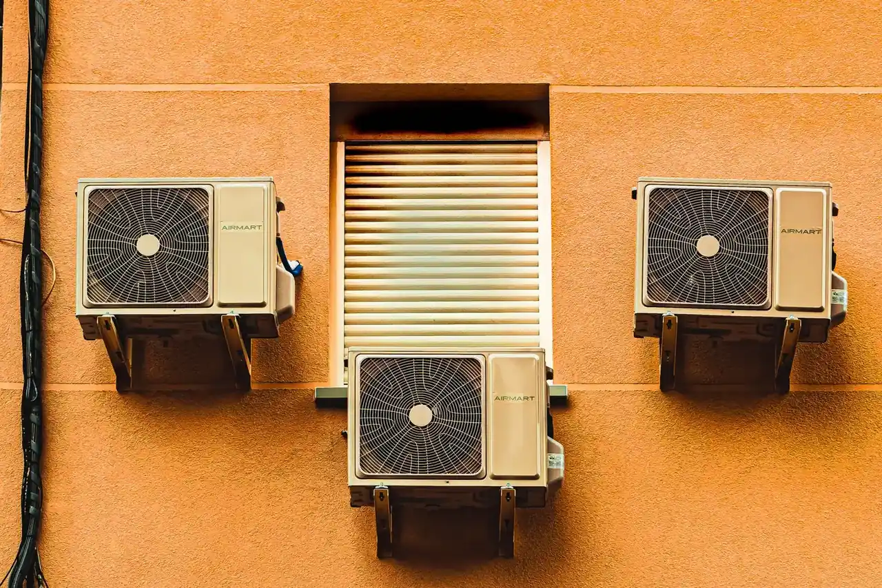 Técnico comprobando y recargando un aire acondicionado doméstico con manómetro y botella de refrigerante — Recargar el aire acondicionado de casa: cuándo es necesario y cuánto cuesta