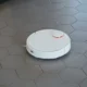 Robot aspirador y fregasuelos industrial limpiando el suelo de una oficina moderna junto a su estación de carga.