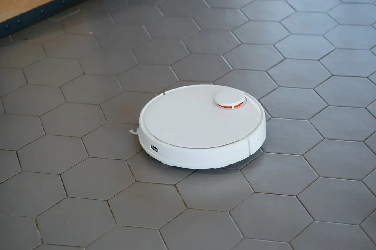 Robot aspirador y fregasuelos industrial limpiando el suelo de una oficina moderna junto a su estación de carga.