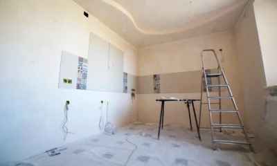 Técnico en una escalera atornillando una campana extractora de techo en una cocina moderna, imagen para el artículo "Cómo instalar una campana extractora de techo sin errores".