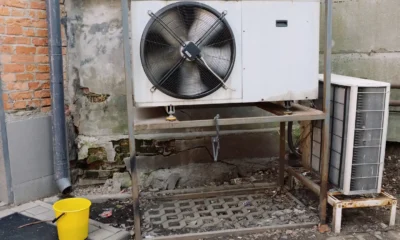Fotografía sobre normativa aire acondicionado comunidades vecinos: técnico instalando una unidad exterior en la fachada de un edificio residencial.