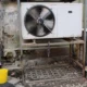 Fotografía sobre normativa aire acondicionado comunidades vecinos: técnico instalando una unidad exterior en la fachada de un edificio residencial.