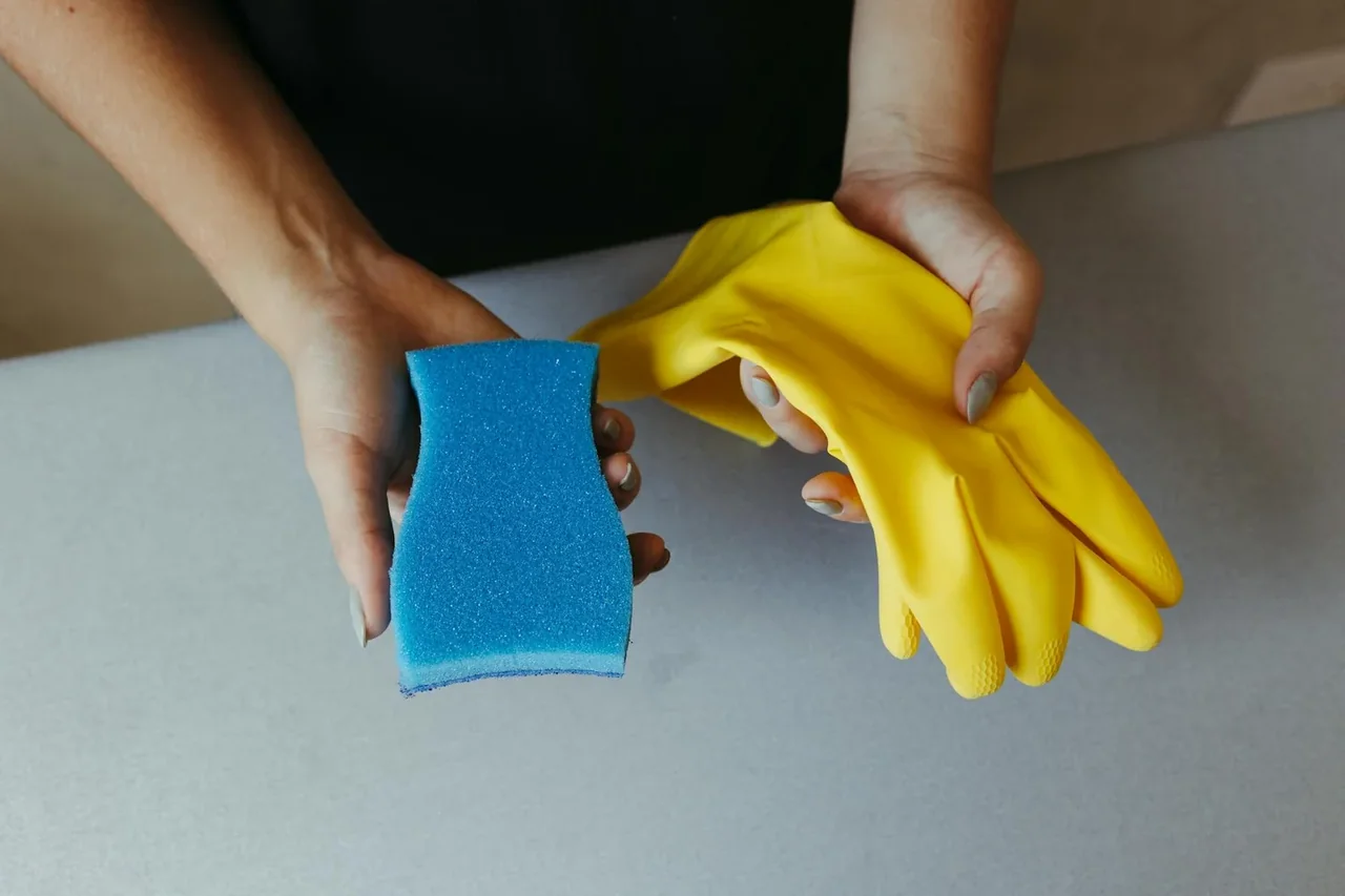 Imagen de productos de limpieza de cocina en la encimera, mostrando desinfectantes, paños y esponjas para limpiar superficies