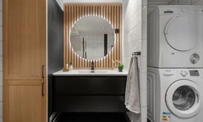 Mueble para lavadora y secadora en torre ikea en una lavandería pequeña con lavadora y secadora apiladas junto a estantes de almacenaje