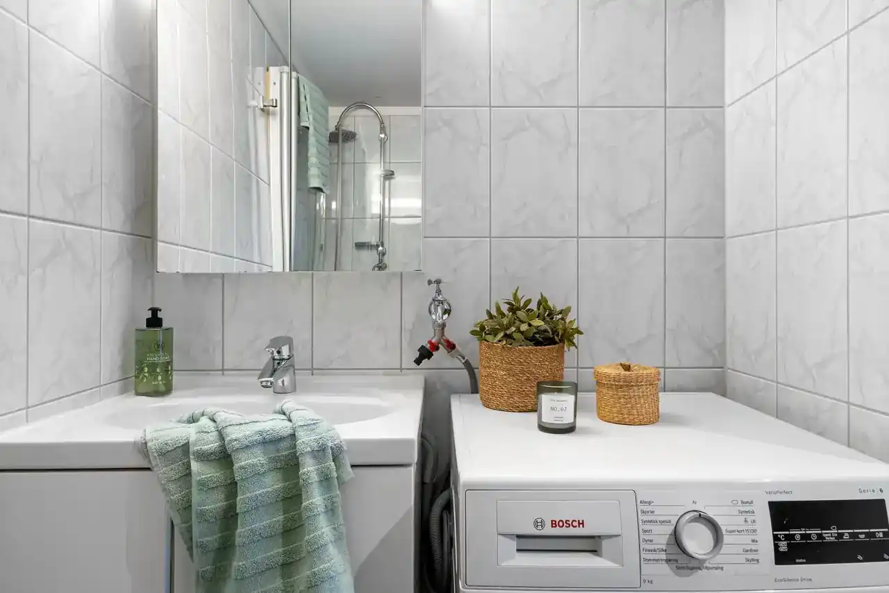 Foto de una lavadora Bosch en casa con una mano pulsando el panel para ilustrar como resetear lavadora bosch
