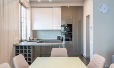 Lavavajillas integrable de 45 cm: medidas, precios y claves, lavavajillas estrecho empotrado en una cocina moderna mientras una persona mide el hueco con una cinta métrica.