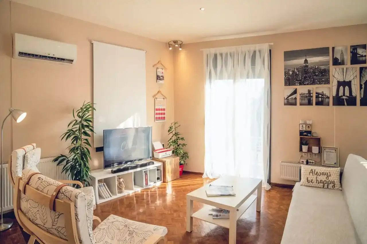Salón con aire acondicionado, ventilador y factura de luz sobre la mesa, ilustrando Qué gasta más el aire acondicionado o el ventilador