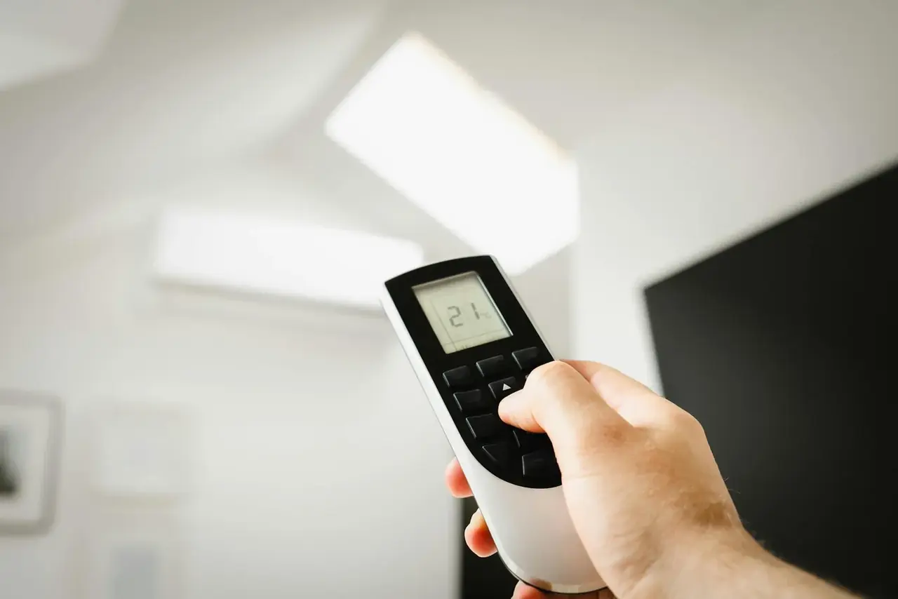 Termostato en sala ajustando la temperatura para reducir consumo energía aire acondicionado.
