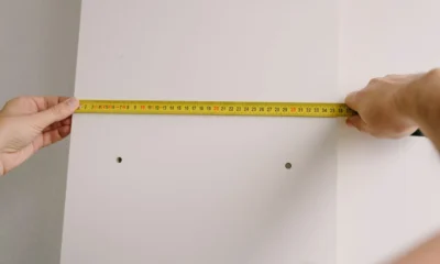 Persona midiendo un televisor de 65 pulgadas medidas con cinta métrica en el salón antes de comprarlo.