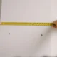 Persona midiendo un televisor de 65 pulgadas medidas con cinta métrica en el salón antes de comprarlo.