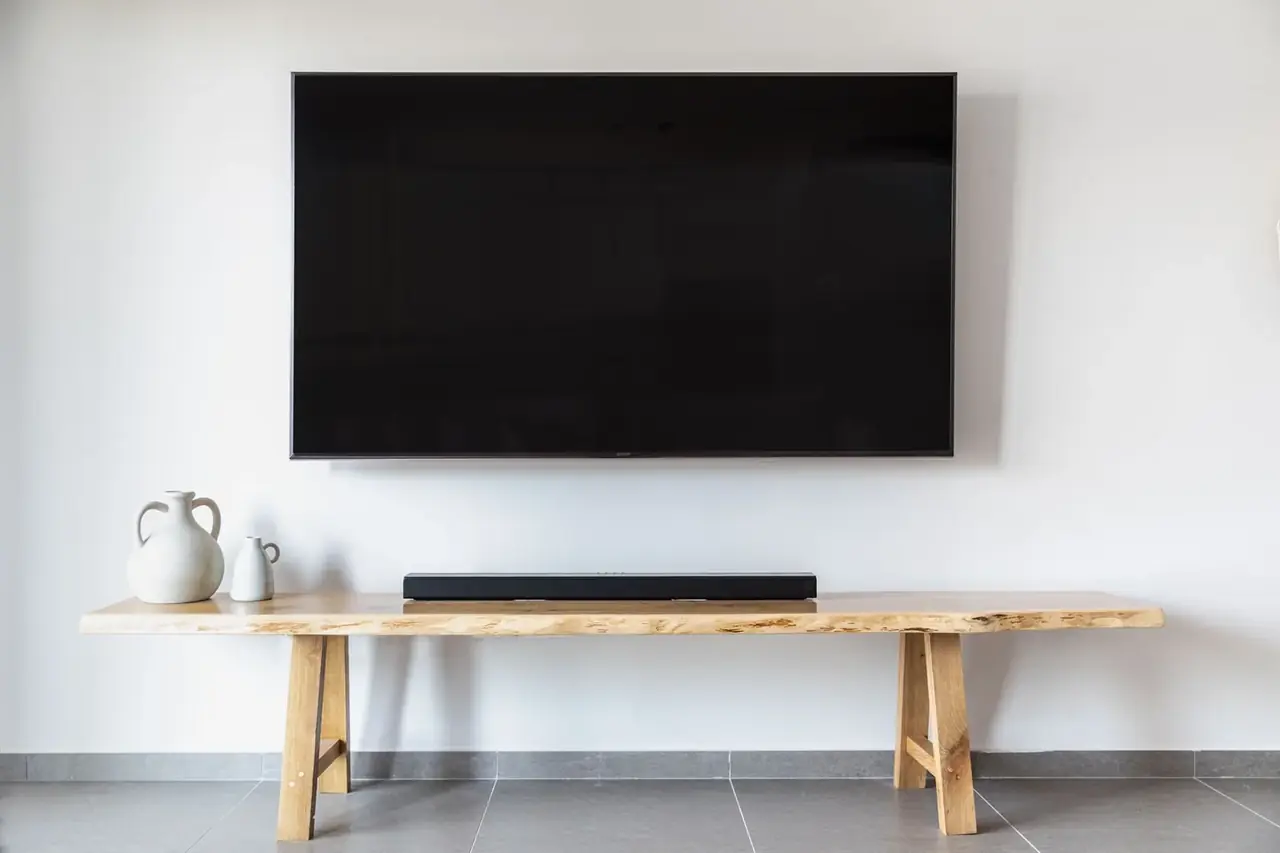 Salón moderno con una barra de sonido para televisor Samsung junto a la televisión sobre un mueble bajo.