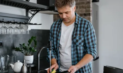 Un técnico revisa el filtro de un lavavajillas no desagua pero la bomba funciona bajo la encimera de la cocina.