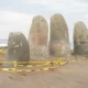 Mano pulsando el botón del modo turbo aire acondicionado en un mando a distancia, con la unidad split montada en la pared de un salón al fondo
