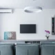 Persona ajustando el mando del aire acondicionado a 26 grados en un salón moderno con la unidad split visible en la pared