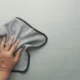 Manos que limpian cuidadosamente la parte superior de una freidora de aire con un paño microfibra, ilustrando Cómo limpiar la freidora de aire por arriba sin dañarla