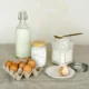 Frascos y manos preparando ingredientes para Cómo hacer un lavavajillas casero eficaz y económico: tarros con bicarbonato y ácido cítrico sobre la encimera de la cocina.