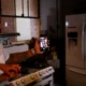 Persona en cocina moderna controlando un frigorífico inteligente con el móvil — Novedades de electrodomésticos en CES 2026: lo que cambia en el hogar