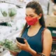 Persona consulta en el móvil una nevera que avisa caducidad alimentos mientras revisa los productos del frigorífico