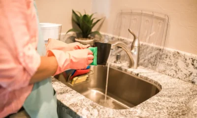 Persona limpiando el interior de la nevera con una esponja y un cuenco de bicarbonato sobre la encimera, ilustrando Cómo quitar el mal olor de la nevera sin recurrir a trucos vacíos