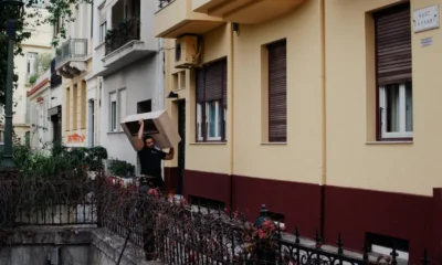 Persona instalando un cubre de listones de madera alrededor del motor exterior en un balcón — Cómo ocultar el motor exterior con un cubre aire acondicionado Ikea integrando la unidad con la estética del espacio.