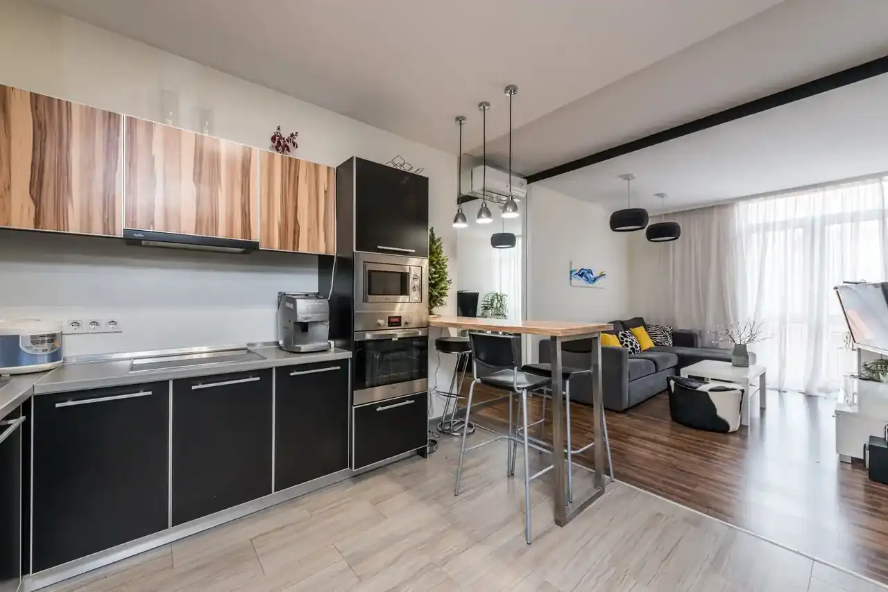 Cocina abierta al salón moderna con una persona cargando un lavavajillas integrado; imagen representativa para Lavavajillas silencioso para cocina abierta al salón: guía de compra.