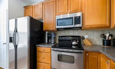 Persona midiendo el ancho de un frigorífico americano estrecho en una cocina compacta — imagen para Frigoríficos americanos estrechos: cómo elegir el modelo adecuado.
