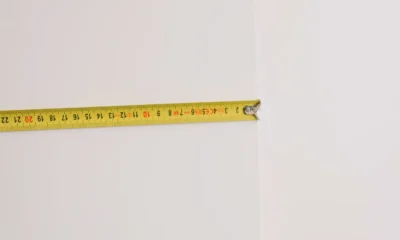 Persona midiendo el espacio para instalar una televisión, ilustrando medidas de televisores en centimetros en un salón