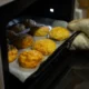 Persona colocando una bandeja de alimentos en un horno inteligente con pantalla táctil que muestra iconos de reconocimiento — Horno que reconoce los alimentos: cómo funciona y qué aporta