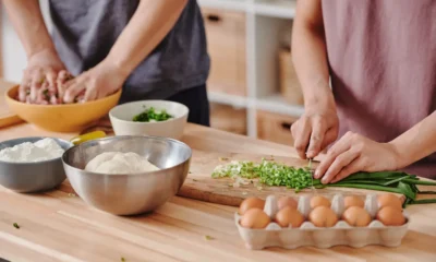 Persona usando un robot de cocina en una cocina moderna para preparar verduras y masa, ideal para ilustrar qué hace un robot de cocina.