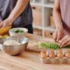 Persona usando un robot de cocina en una cocina moderna para preparar verduras y masa, ideal para ilustrar qué hace un robot de cocina.