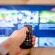 Persona usando el mando frente a un televisor LG para mostrar como sintonizar canales televisor lg en el menú de ajustes.