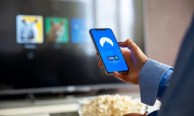Persona consultando SmartThings en el móvil junto al televisor para entender qué es el modo ai energy en samsung.