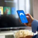 Persona consultando SmartThings en el móvil junto al televisor para entender qué es el modo ai energy en samsung.