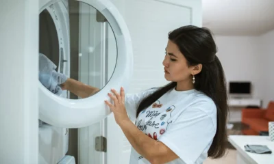 Lavadora y secadora modernas con panel digital y un smartphone sobre la encimera, imagen representativa de Samsung AI Laundry Combo: precio, funciones y ficha técnica en un lavadero luminoso
