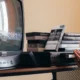 Persona desenchufando un decodificador frente a un televisor antiguo, ilustrando que Movistar Plus+ dejará de ser compatible con televisores antiguos pronto.