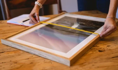 Persona midiendo un televisor con una cinta métrica para ilustrar Cuánto mide un televisor de 32 pulgadas en centímetros en un artículo sobre dimensiones de televisores.